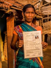 Opens popup gallery with A woman shows her joint land rights title